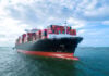 Aerial side view of cargo ship carrying shipping containers for export