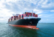 Aerial side view of cargo ship carrying shipping containers for export