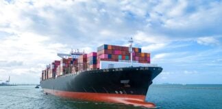Aerial side view of cargo ship carrying shipping containers for export