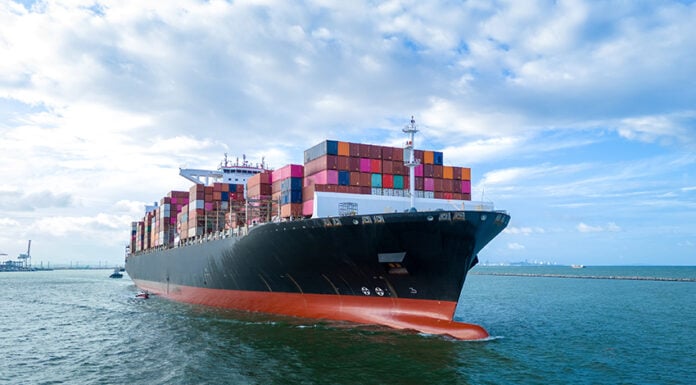 Aerial side view of cargo ship carrying shipping containers for export