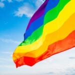 Pride flag flying with blue sky in the background