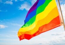 Pride flag flying with blue sky in the background