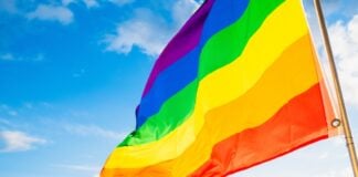 Pride flag flying with blue sky in the background