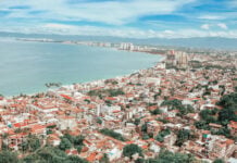 Coastline of Puerto Vallarta during the daytime, densely packed with similar white and red adobe multistory buildings.