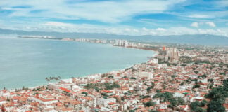 Coastline of Puerto Vallarta during the daytime, densely packed with similar white and red adobe multistory buildings.