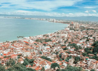 Coastline of Puerto Vallarta during the daytime, densely packed with similar white and red adobe multistory buildings.