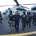 Mexican troops escort a handcuffed man away from a helicopter
