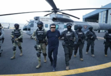 Mexican troops escort a handcuffed man away from a helicopter