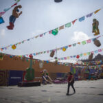A woman walks through Mexico City's empty Zócalo, under color banners and World Cup decorations