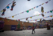 A woman walks through Mexico City's empty Zócalo, under color banners and World Cup decorations