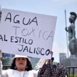 Woman holding up a sign protesting toxic Guadalajara tap water