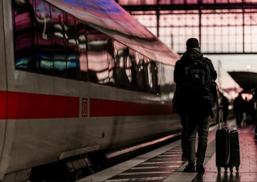 An traveler with a backpack stands by a ICE high-speed train in Europe