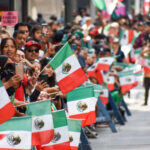 Spectators wave Mexican flags at a 2022 Mexican Independence Day parade in New York City.