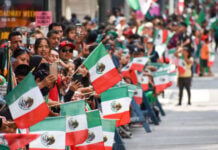 Spectators wave Mexican flags at a 2022 Mexican Independence Day parade in New York City.