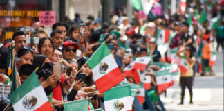 Spectators wave Mexican flags at a 2022 Mexican Independence Day parade in New York City.