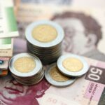 Mexican peso money bills and centavo coins pile on table. Mexico coins on banknotes of MXN currency close up