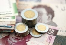 Mexican peso money bills and centavo coins pile on table. Mexico coins on banknotes of MXN currency close up