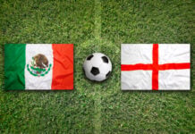 England and Mexico flags on a soccer field with a soccer ball
