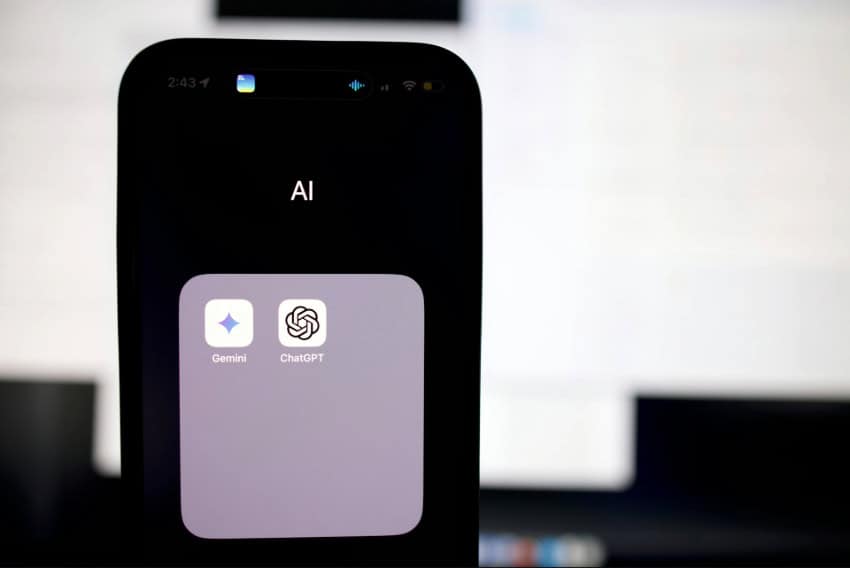 A phone displays AI application icons with a computer screen in the background