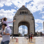 Families play in the fountains of Mexico City's Monument to the Revolution on a warm day.