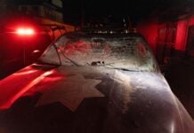 Damaged police car with shattered windshield and dust in Mexico.