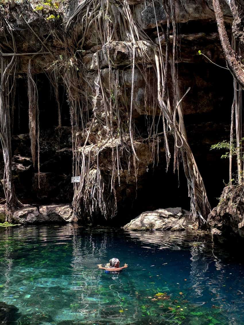 a woman swimming in a blue lagoon at a cenote in Yucatan