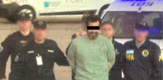 Ex-Navy rear admiral Fernando Farías, handcuffed, accompanied by five federal agents