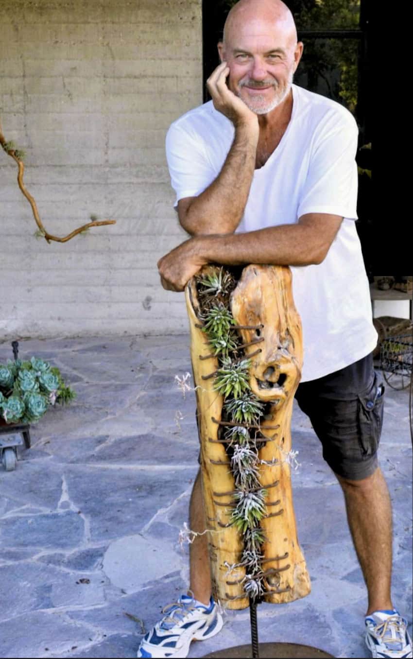 An artist stands with his botanical sculpture.