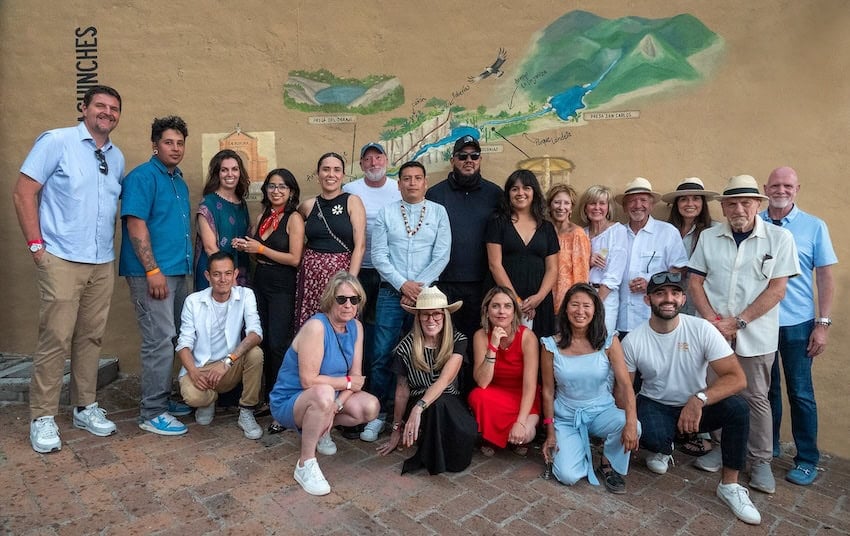 A group of artists and patrons stand in front of an arroyo mural in San Miguel de Allende, Mexico.