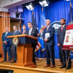 US officials with a poster displaying the CJNG leaders and associated rewards for their capture