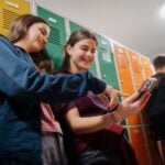 Teen students hanging out in school hallway by lockers.