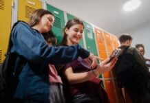 Teen students hanging out in school hallway by lockers.