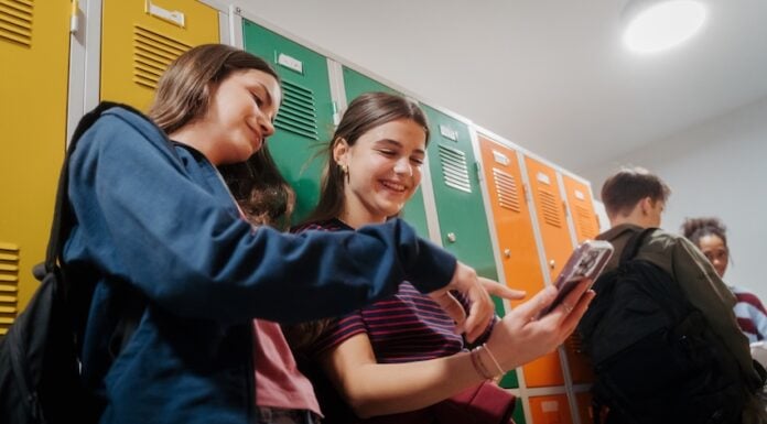 Teen students hanging out in school hallway by lockers.