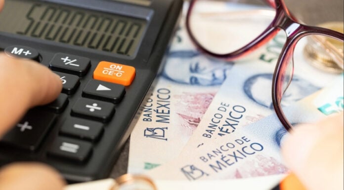 mexican pesos with a calculator and a pair of glasses on a table
