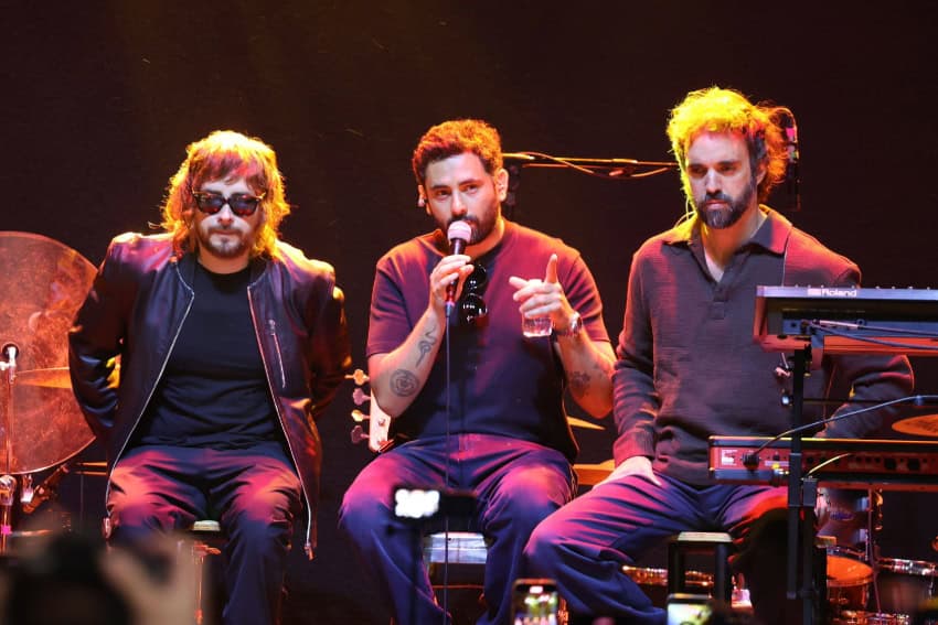 Jonathan Meléndez speaks at a microphone with his Camilo Séptimo bandmates