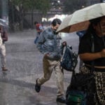Mexico City residents with umbrellas and jackets run through a rain story at the Glorieta de Insurgentes on Sept. 2, 2026
