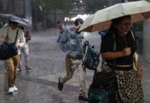 Mexico City residents with umbrellas and jackets run through a rain story at the Glorieta de Insurgentes on Sept. 2, 2026
