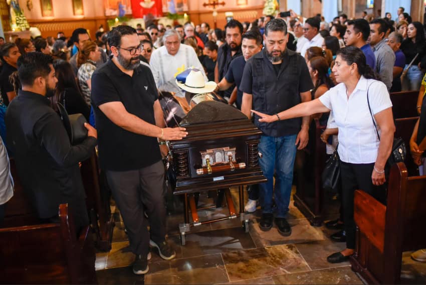 People stand around a coffin at the funeral of Deputy Zenyazen Escobar García.