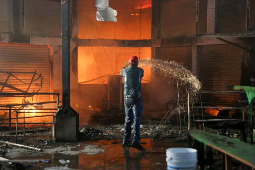A man throws a bucket of water toward a burning wall in the Acapulco Central Market