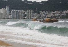 Heavy rain and waves on an Acapulco beach, as Hurricane Polo passes by offshore