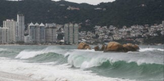 Heavy rain and waves on an Acapulco beach, as Hurricane Polo passes by offshore