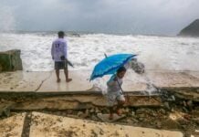 two people duck from splattering ocean water as a hurricane approaches Mexico