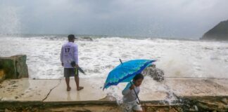 two people duck from splattering ocean water as a hurricane approaches Mexico