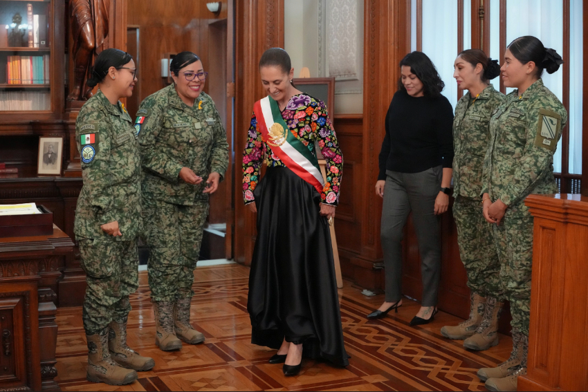 President Sheinbaum in a dark dress with colorful Mexican floral embroidery