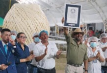 A man holds up a Guiness World Record plaque in front of a giant ball of quesillo string cheese