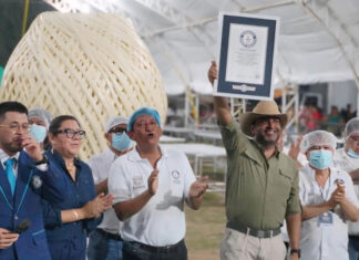 A man holds up a Guiness World Record plaque in front of a giant ball of quesillo string cheese