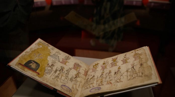 The yellowed pages of the Azcatitlan Codex, showing illustrations of Indigenous people in a line under a pyramid and columns bearing a variety of symbols