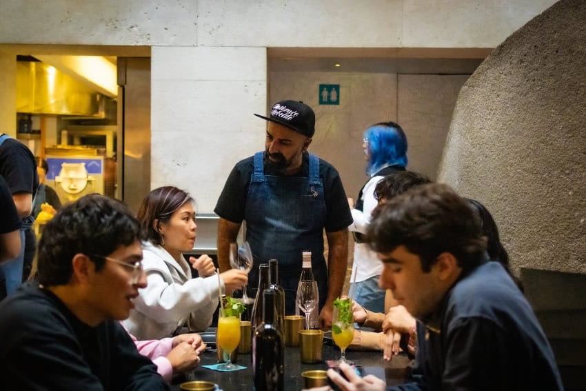 "Pay What You Can" dinner in Mexico City with diners conversing with the chef