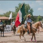 Cow sorting event in San Miguel de Allende, with woman on horseback waving the Mexican flag