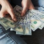 Woman fanning a pile of U.S. 100 dollar bills.